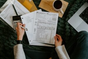 Parents review tax forms and receipts at a kitchen table beside documents for children and child care.