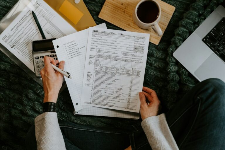 Parents review tax forms and receipts at a kitchen table beside documents for children and child care.